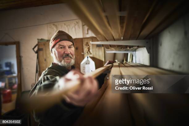 senior man taking piece of wood from shelf - snickeriarbete bildbanksfoton och bilder