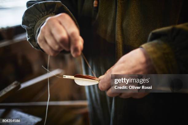 close-up of man working on arrow in workshop - bow and arrow stock pictures, royalty-free photos & images