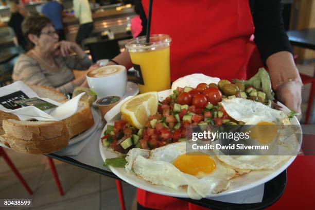 Waitress serves breakfast for two, including eggs, cheeses, salad, orange juice, coffee and fresh baked bread at the Aroma espresso bar on March 11,...