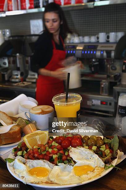 Waitress prepares a tray of breakfast for two, including eggs, cheeses, salad, orange juice, coffee and fresh baked bread at the Aroma espresso bar...
