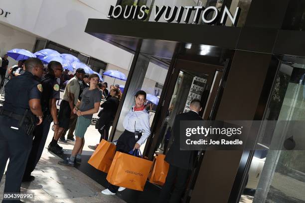 Staff member helps a customer with his bags as people flock to the Louis Vuitton store to purchase limited edition supreme and Louis Vuitton...