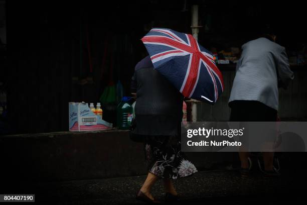 An elderly woman is seen with an umbrella with the British flag in the center of the city on a stormy day on 30 June, 2017.