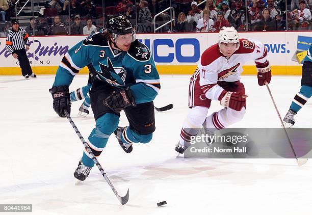 Defenseman Douglas Murray of the San Jose Sharks skates the puck through center ice while being chased by Radim Vrbata of the Phoenix Coyotes on...