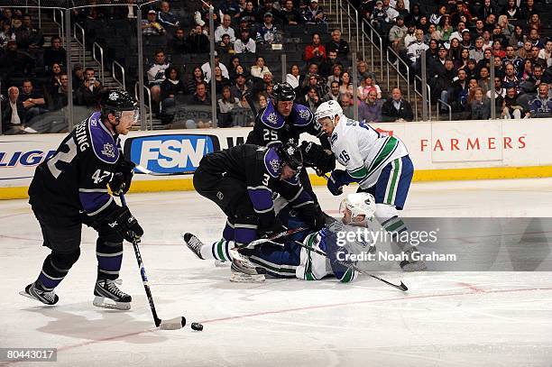 Tom Preissing of the Los Angeles Kings drives the puck away from Alexander Edler, Ryan Shannon of the Vancouver Canucks as they get tangled up with...