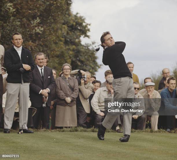 Gary Player of South Africa drives off the 4th tee as Arnold Palmer and the spectators look on during the first Piccadilly World Match Play...