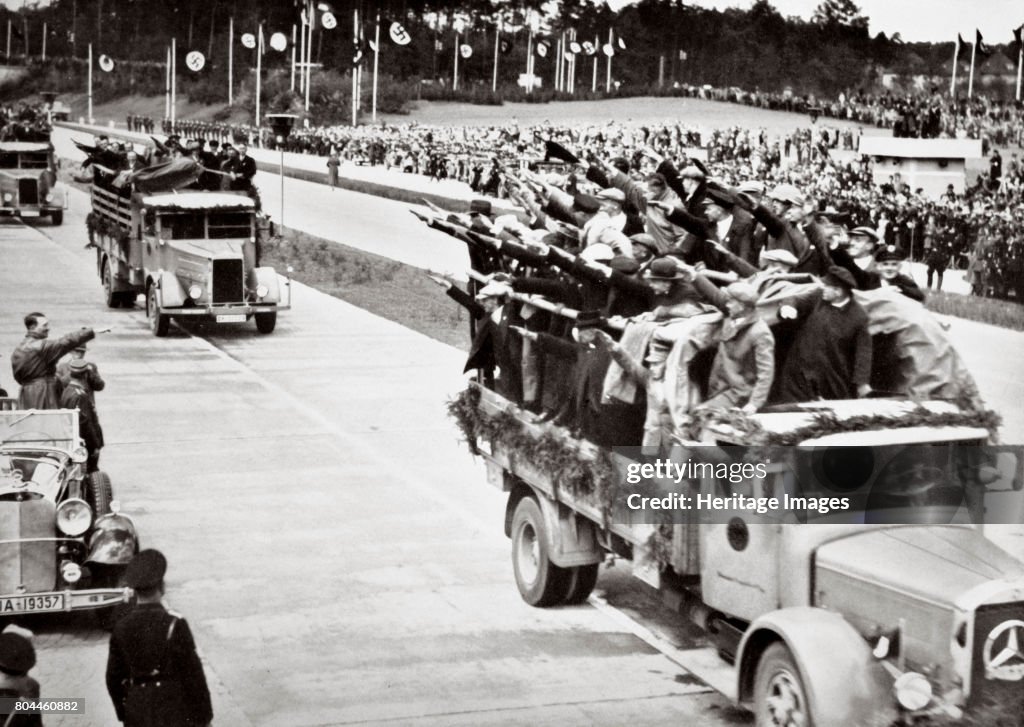 Hitler Rabble Rouser Labourers salute Hitler from packed trucks on a Nazi-built road ...