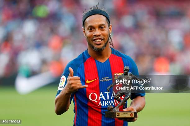 Former Barcelona's Brazilian forward Ronaldinho poses with the trophy for the best player after a charity football match between Barcelona Legends vs...