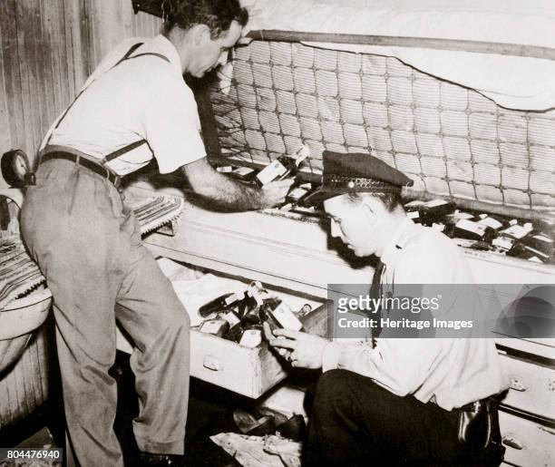 Enforcing prohibition, Norfolk, Virginia, USA, 1920s. Law enforcement agents examining at a cache of 191 pint bottles found underneath a sailor's...