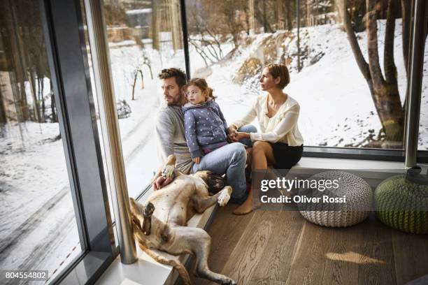 family with dog at home sitting at the window - mann frau hund zuhause stock-fotos und bilder