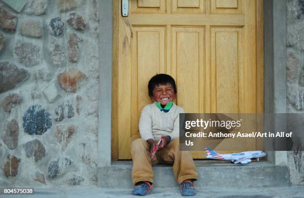 Local boy with red cheeks playing alone on November, 2016 in Parque Nacional de Sajama, Bolivia.