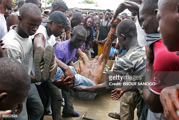 Ivorian demonstrators carry the body of a man killed by Ivorian police on April 1, 2008 when police fired live bullets and tear gas to break up...