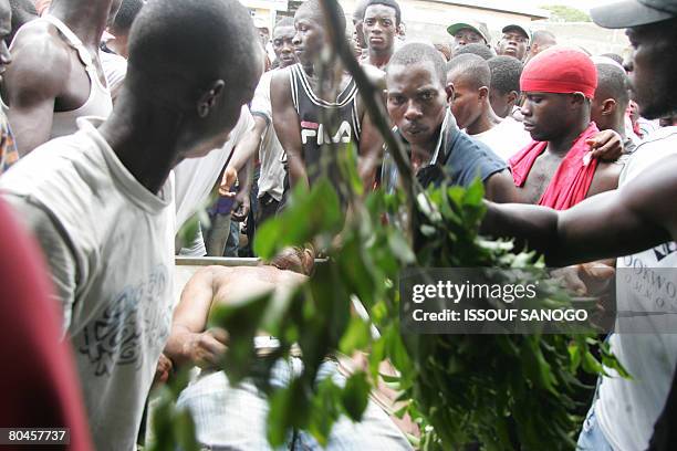 Ivorian demonstrators carry the body of a man killed on April 1, 2008 when police fired live bullets and tear gas to break up protests against rising...