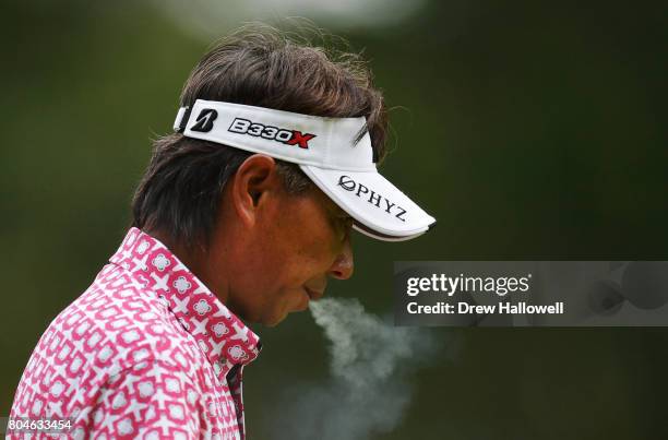 Kohki Idoki of Japan blows out smoke as he walks off the second tee box during the second round of the 2017 U.S. Senior Open Championship at Salem...