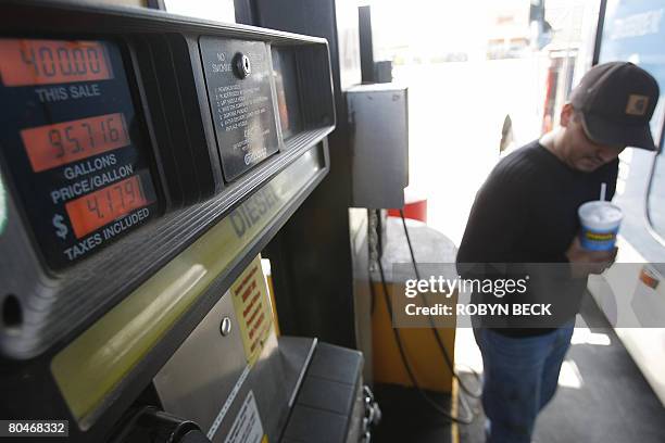 Trucker Paul Cornejo has a soft drink as a fuel pump displays the cost of fueling his tractor trailer at USD 4.179 per gallon, at a truck stop and...