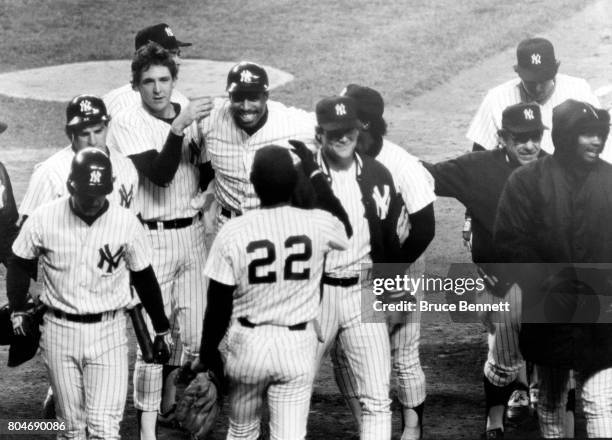 Dave Winfield of the New York Yankees is congratualted by teammates Dave Righetti, Omar Moreno, Dan Pasqua, Rickey Henderson and manger Yogi Berra...