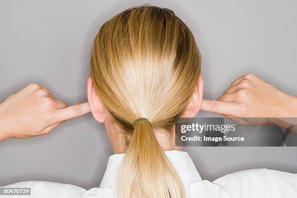 a woman with her fingers in her ear - woman fingers in ears stock pictures, royalty-free photos & images