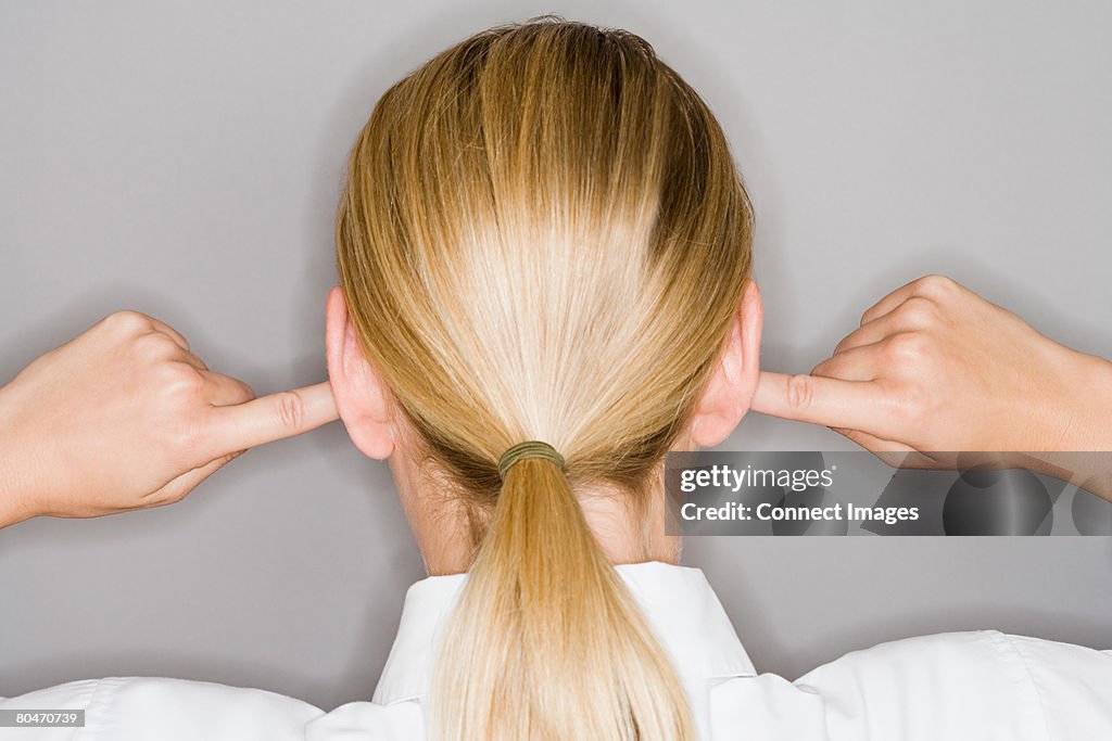 A woman with her fingers in her ear