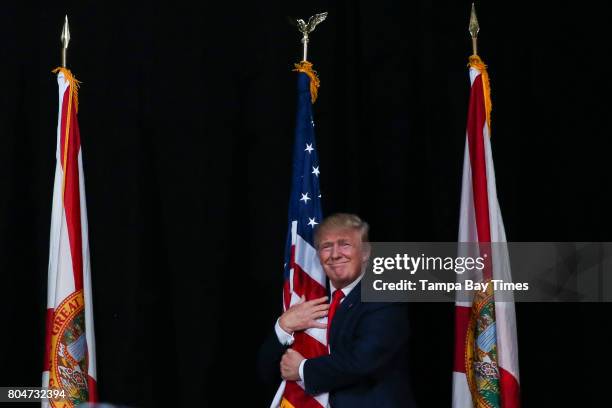 Donald Trump hugs the American Flag as he takes the stage during the rally at the MidFlorida Credit Union Amphitheatre in Tampa, Florida, on Monday,...