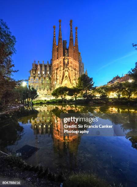 sagrada familia illuminated at dusk and reflected on lake in barcelona, catalonia, spain - barcelona gaudi stock-fotos und bilder