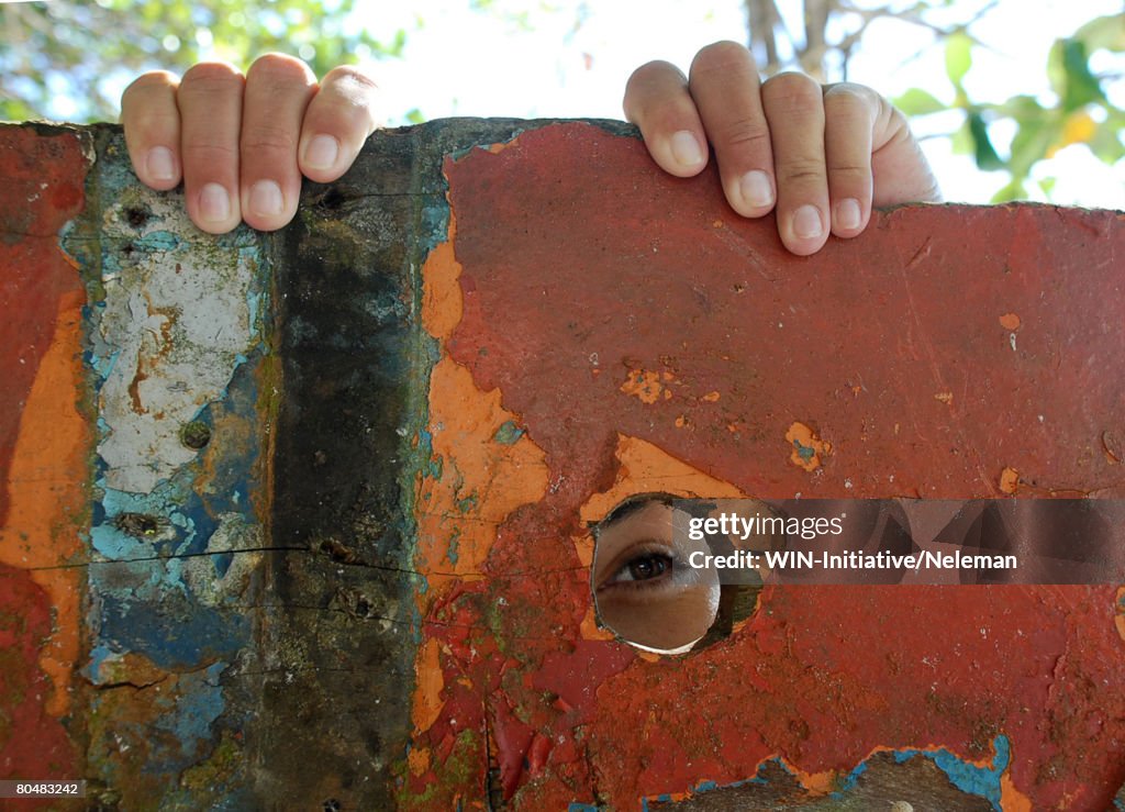 Child spying behind rusted wall