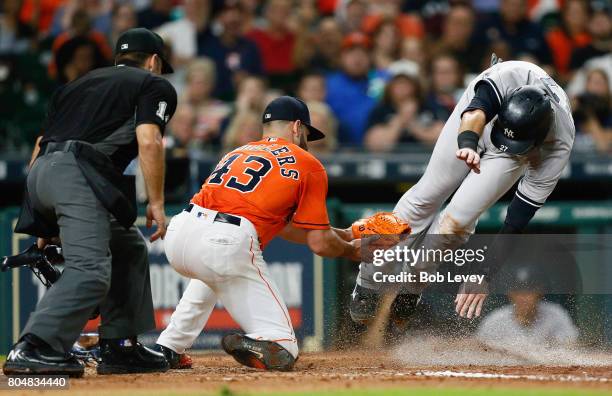 Lance McCullers Jr. #43 of the Houston Astros tags out Austin Romine of the New York Yankees as he atempts to score on a wild pitch in the fourth...