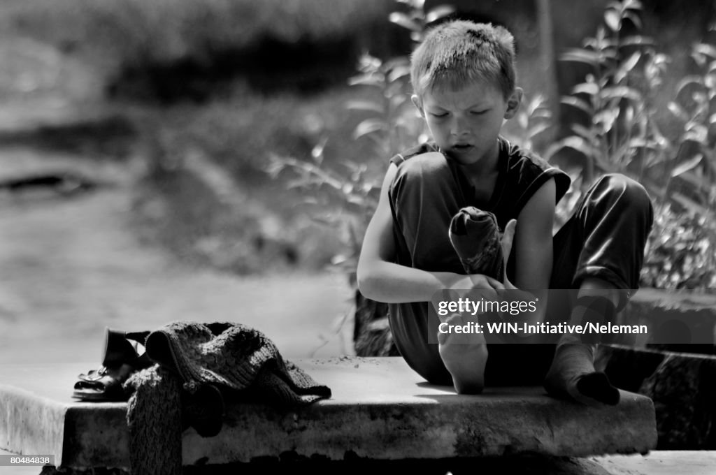 Boy sitting on stone flag, wearing socks (B&W)