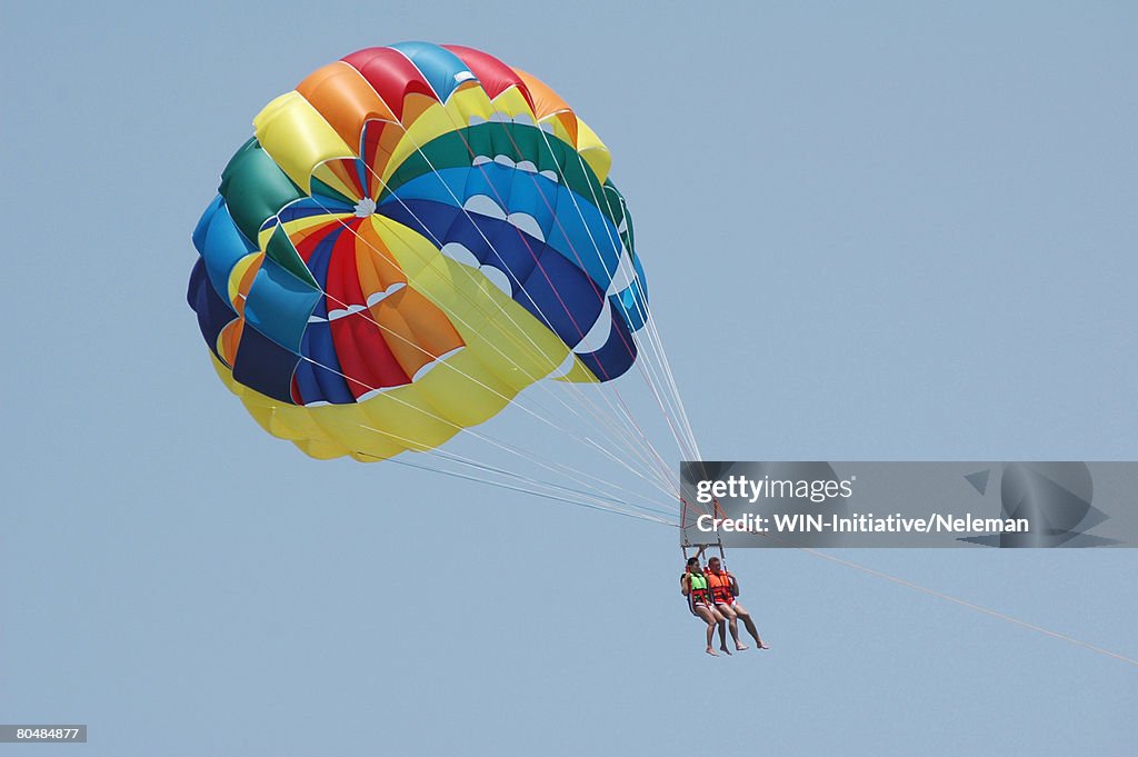 Couple parasailing, low angle view