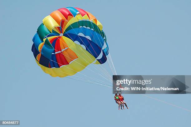 couple parasailing, low angle view - para sailing beach stock pictures, royalty-free photos & images