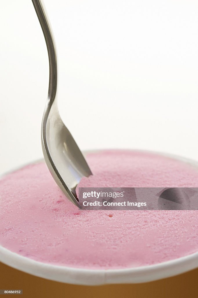 A spoon and container of icecream