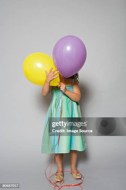 girl hiding behind balloons - child balloon studio photos et images de collection