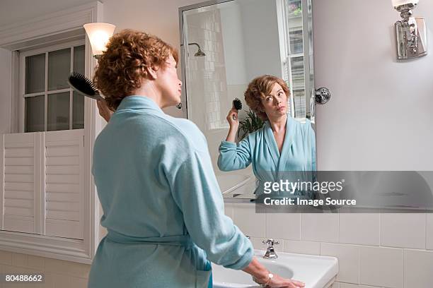 woman brushing hair - bathroom mirror 個照片及圖片檔