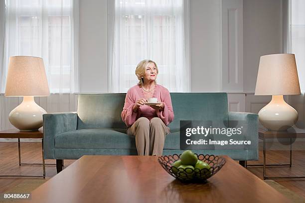 femme dans la salle de séjour - seulement des femmes seniors photos et images de collection