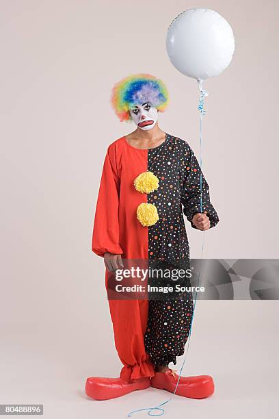 a clown holding a balloon - sad clown stock pictures, royalty-free photos & images