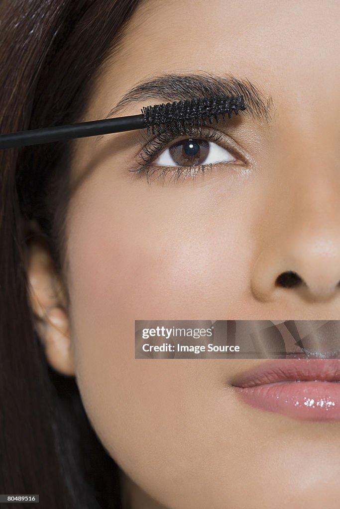 A woman applying mascara