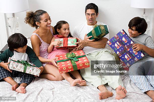 a family in bed with gifts - family with three children stock pictures, royalty-free photos & images