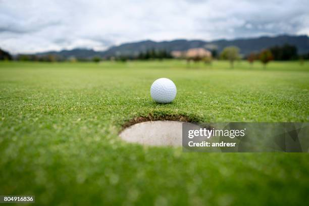 balle de golf va dans le trou dans le vert - trou photos et images de collection