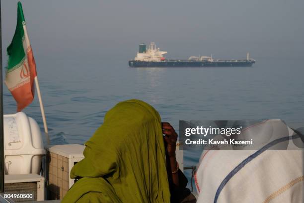 Foreign tourists in veils seen on a passenger boat with the Iranian flag amass in the waters of Strait of Hormuz on May 2, 2017 near Hormuz Island,...