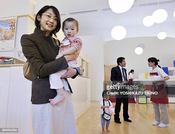 Working mother picks up her baby from a nursery room or "Kangaroom", which is run by Japanese cosmetics giant Shiseido in Tokyo on April 2, 2008....