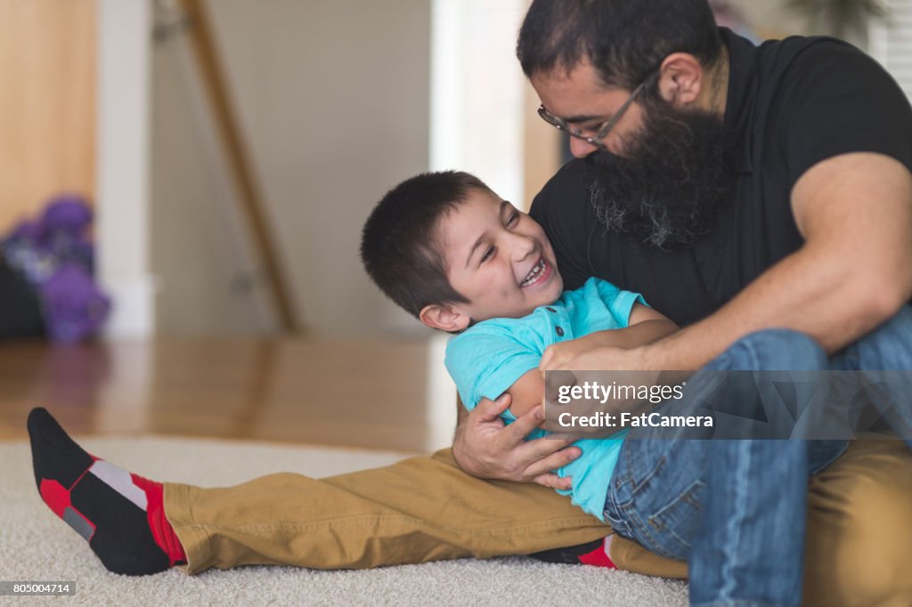 Native American dad worstelt en speelt met zijn zoon in woonkamer