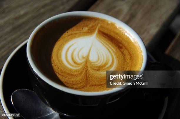 a flat white milk coffee on a wood-slatted table at a sidewalk cafe in canberra, australian capital territory, australia - black milk australia stock pictures, royalty-free photos & images