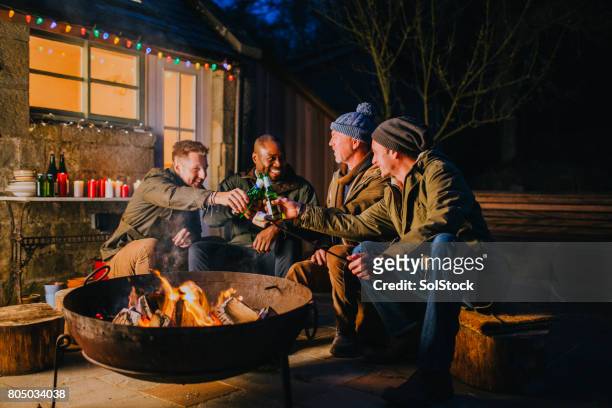 groep mannelijke vrienden verzameld rond een vuurplaats - alleen oudere mannen stockfoto's en -beelden