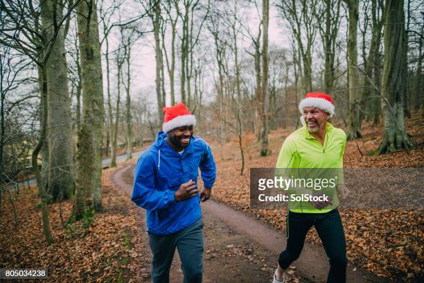 two joggers up the trails in the forest at christmas - santa hat stock pictures, royalty-free photos & images