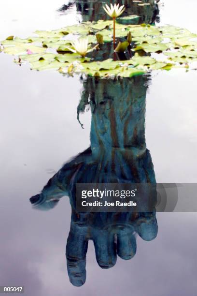 The reflection of a statue, by artist Kenneth Treister, is on display as part of a sculpture depicting thousands of victims crawling into an open...
