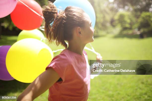 a 10 years old girl running with balloons in a park - girl 10 years old happy stock-fotos und bilder