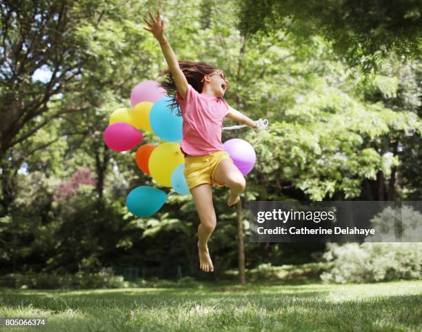 a 10 years old girl jumping with balloons in a park - girl 10 years old happy stock-fotos und bilder