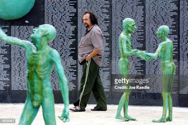 Visitor looks at statues, by artist Kenneth Treister, which are on display as part of a memorial depicting thousands of victims crawling into an open...