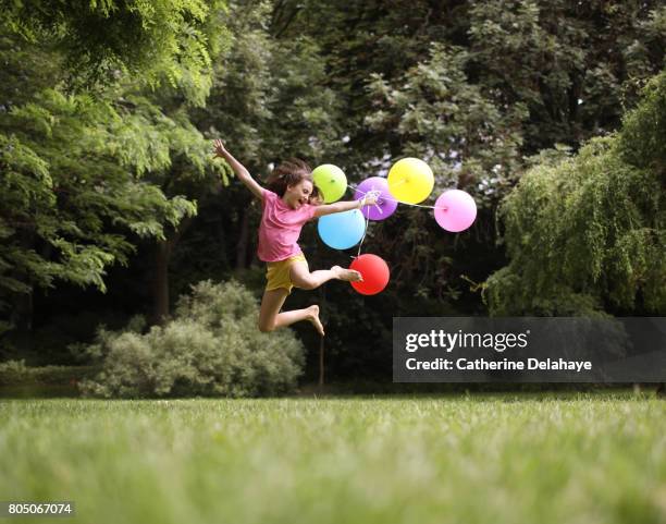 a 10 years old girl jumping with balloons in a park - 10 11 years ストックフォトと画像