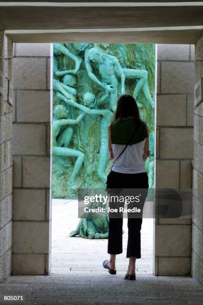 Visitor looks at statues, by artist Kenneth Treister, which are on display as part of a memorial depicting thousands of victims crawling into an open...