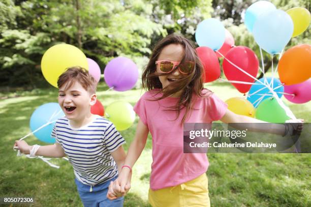 a brother and a sister posing together with balloons - boyshorts fotografías e imágenes de stock