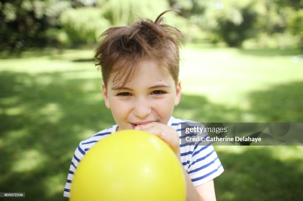 A 8 years old boy with a balloon in a park